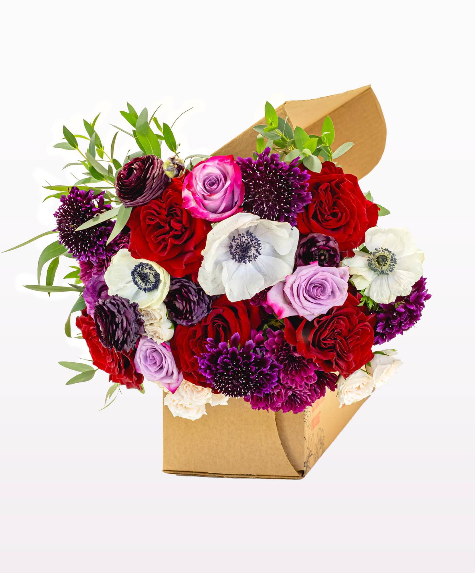 Vibrant floral arrangement in a box featuring roses, anemones, and purple blooms.